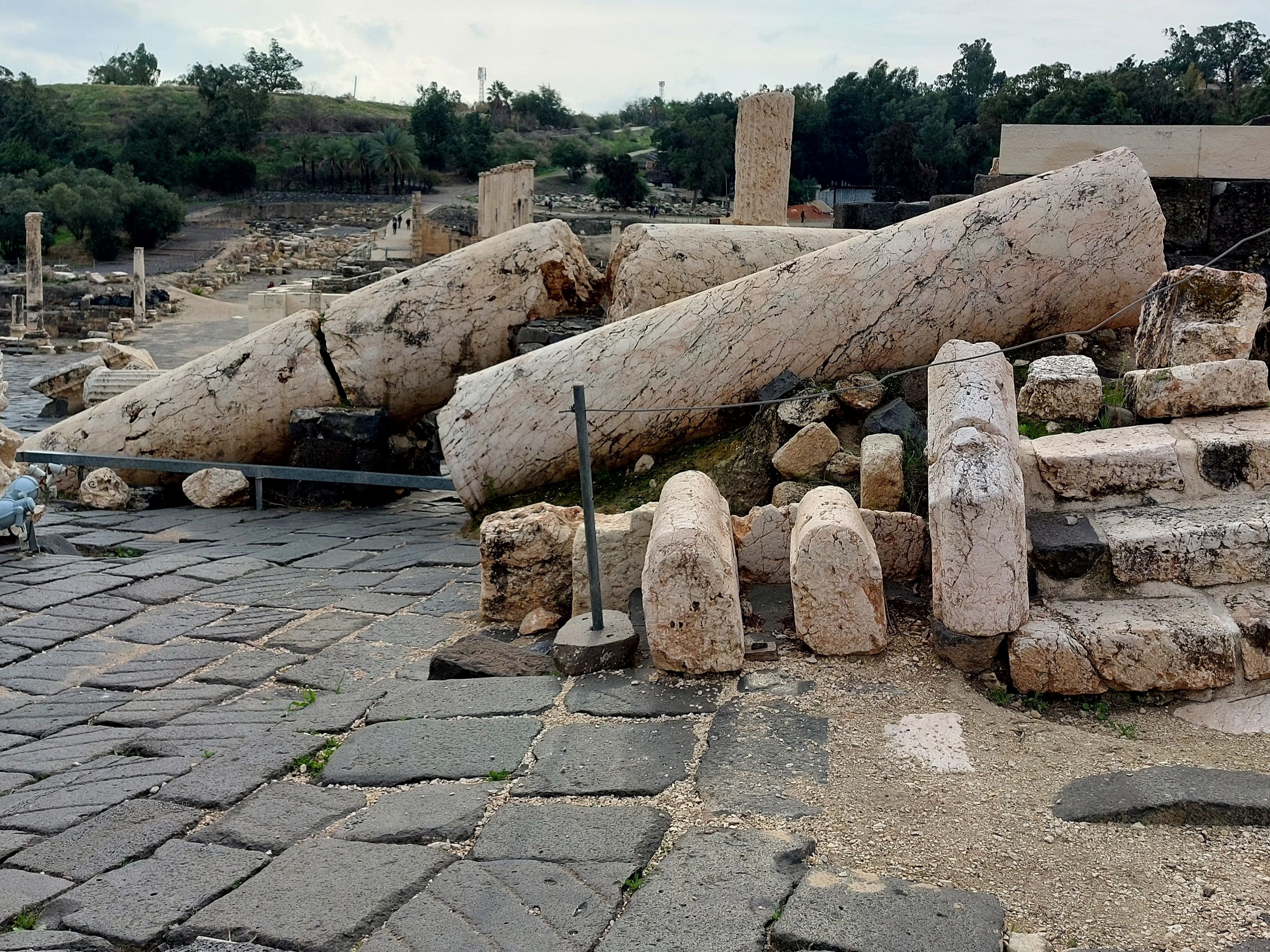 Giant marble columns fallen and scattered across the ancient basalt paving stones of Beth-Shan's main street, toppled by the 749 A.D. earthquake that destroyed the city