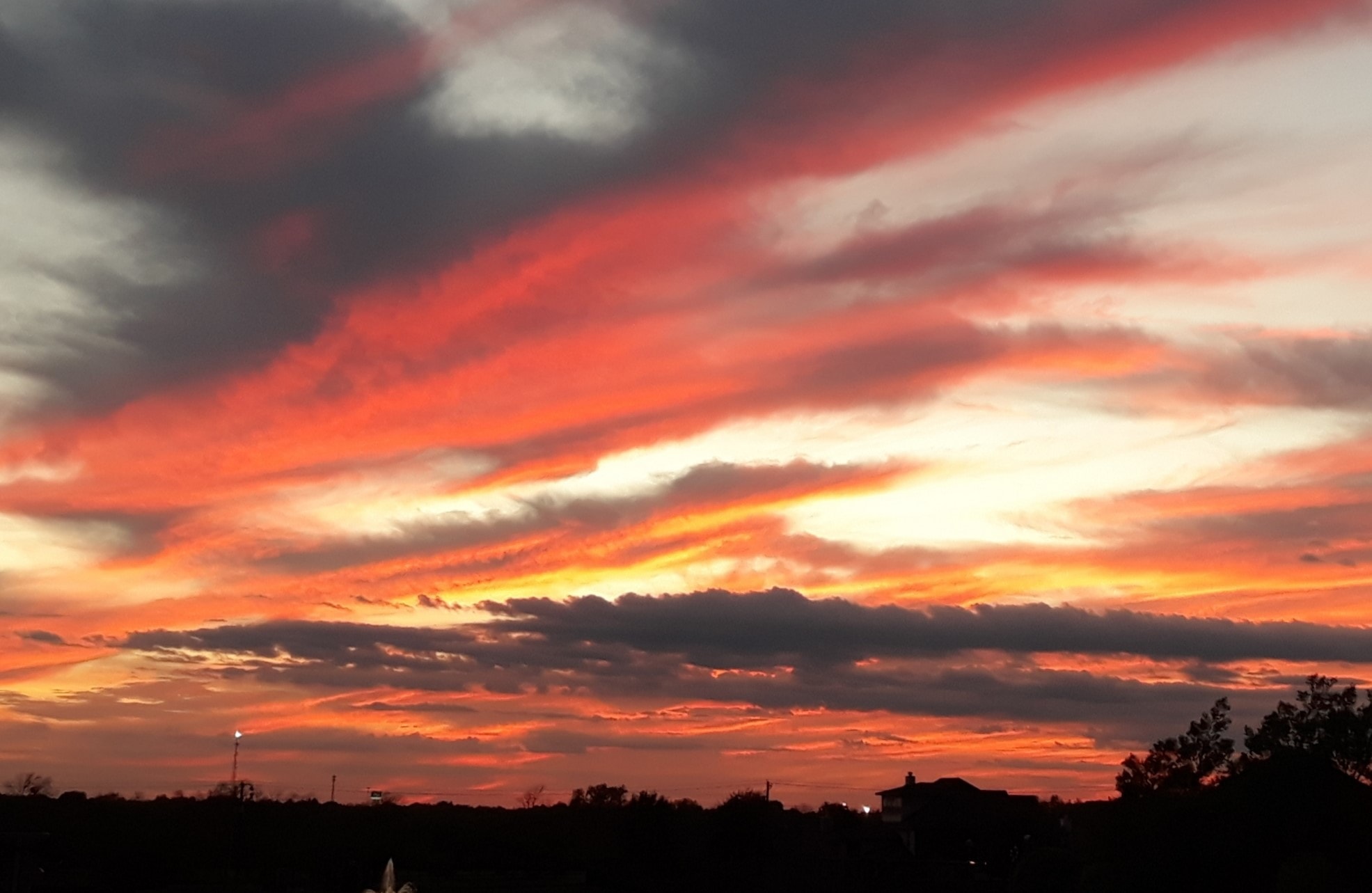 Dramatic fiery sunset with vivid orange and red clouds over a dark silhouetted skyline