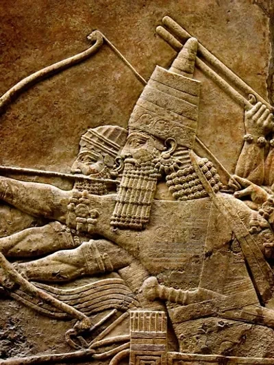 Assyrian stone relief carving showing a king and warriors with bows and spears — detail from an ancient Assyrian palace relief depicting military scenes from the reign of Sennacherib